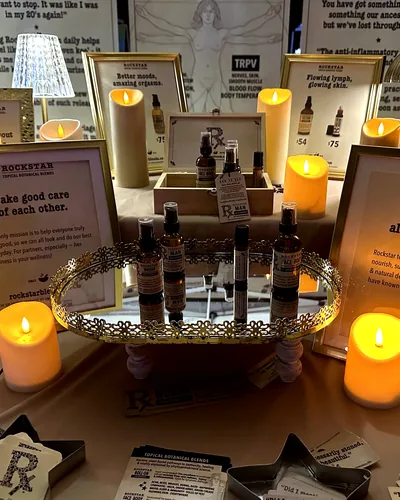 A mirrored tray of amber bottles labelled Rockstar Woman, Man and Face-Body, among flameless candles and gold-framed signs, one reading Take good care of each other.